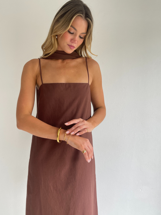 By Nicola Ivy maxi dress in chocolate brown cotton-linen with straight neckline, side slit, column style and chiffon neck tie, ideal for weddings and summer events.