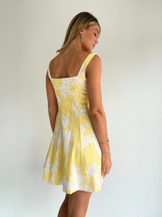 By Nicola Milly mini dress in amarilla flor yellow floral print in cotton linen with  straps and flowy hem, perfect for daytime events and summer occasions. Exclusive to Coco & Lola
